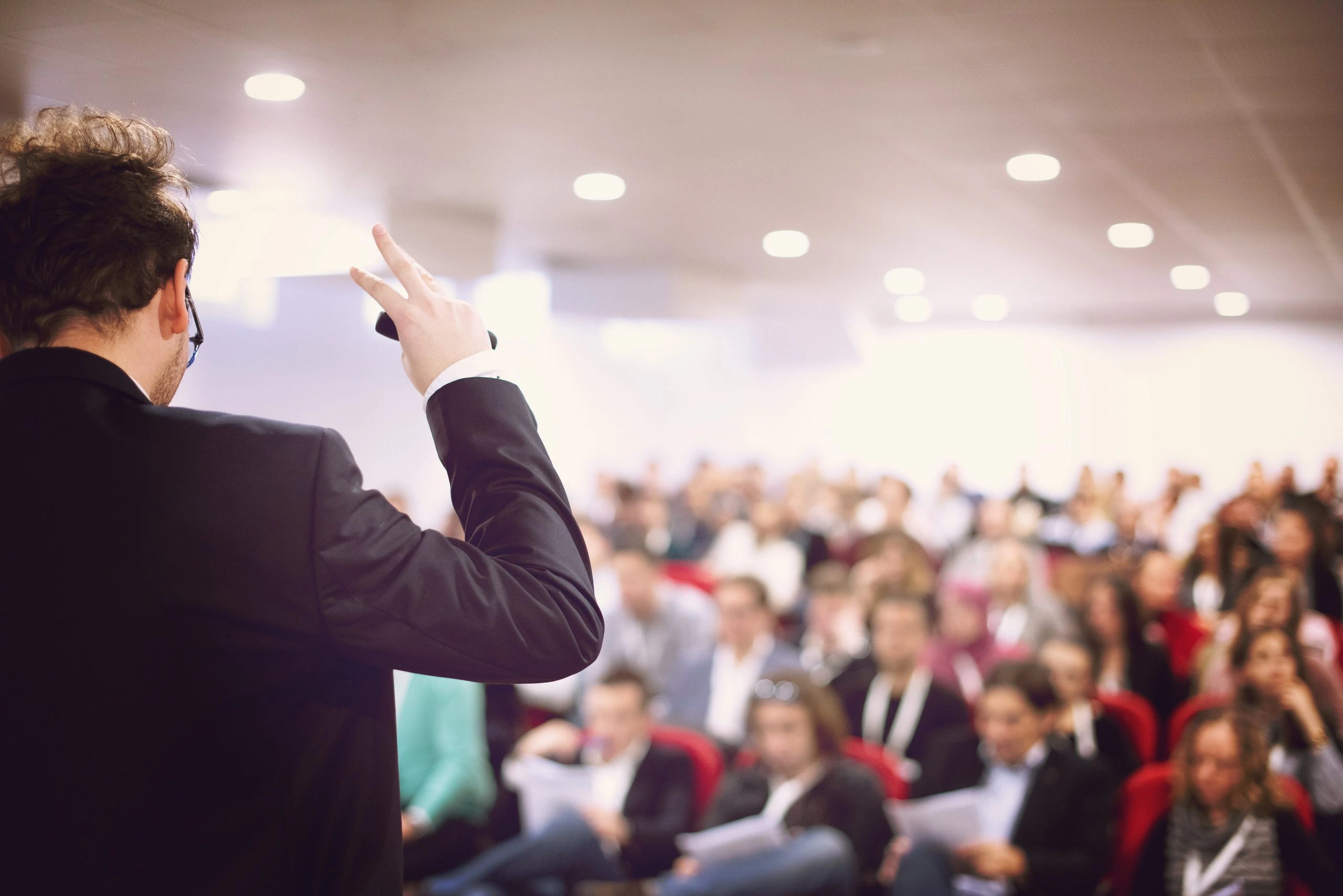 Professional conference event with branded stage, presentation screen, and audience seating