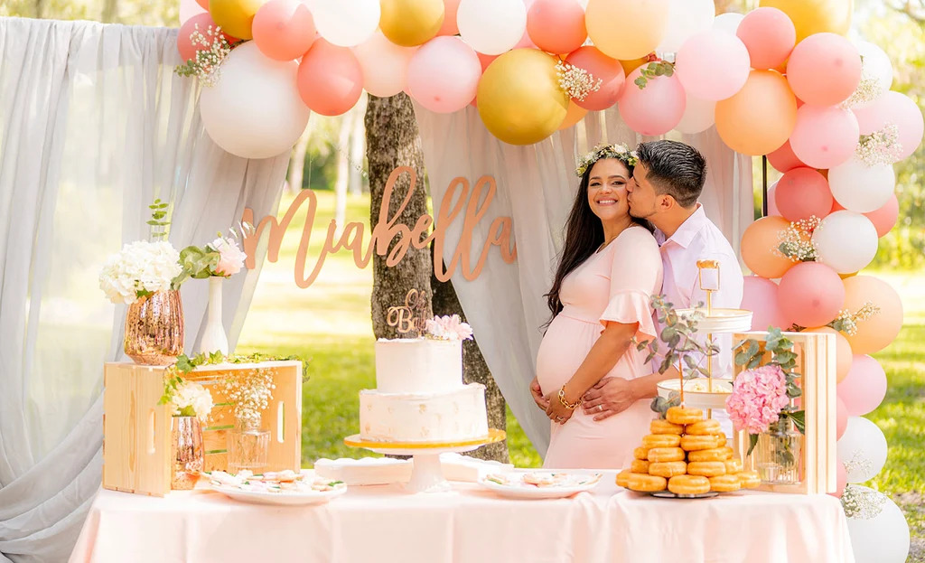 Elegant baby shower celebration with pastel decorations, balloons, floral arrangements, and a beautifully styled backdrop